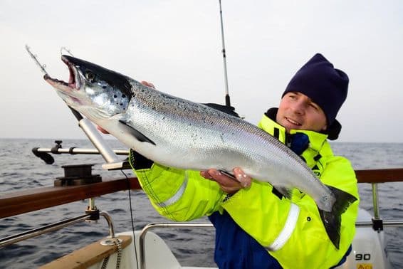 Pesca en el mar, un pescador mostrando orgulloso una gran captura en un barco.