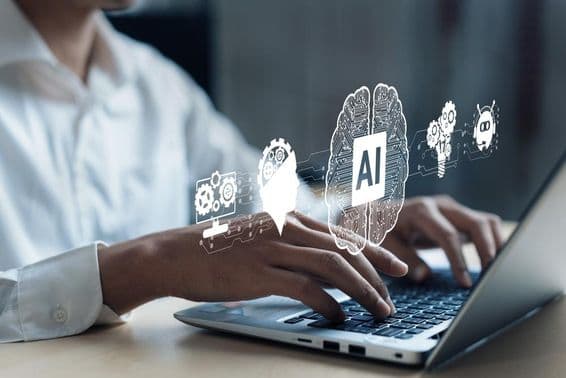 Proyección sobre un cuaderno mostrando un cerebro de IA y otros elementos. Una mano humana trabajando en la computadora.