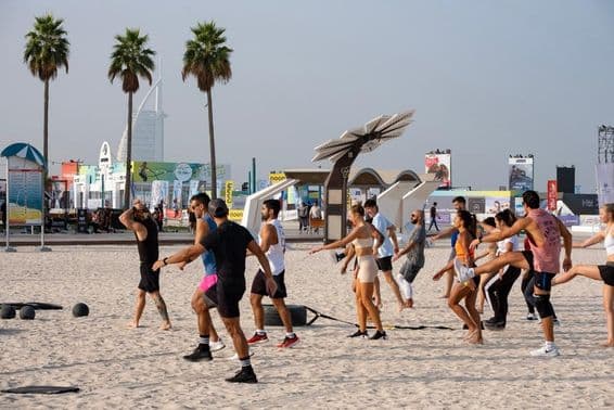 Un grupo de personas ejercitándose en una playa arenosa durante el Desafío de Fitness de Dubái.