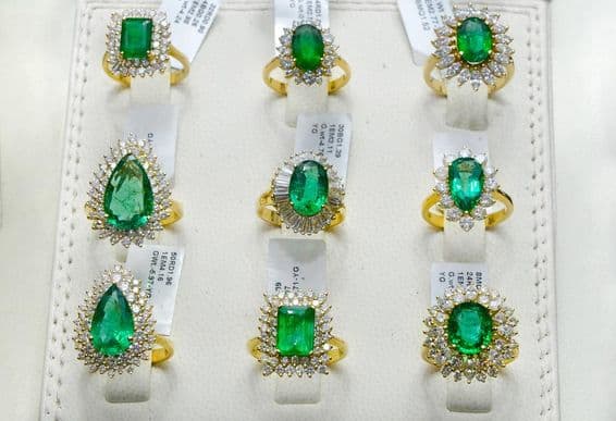 Anillos de esmeralda rodeados de diamantes en un aro de oro.