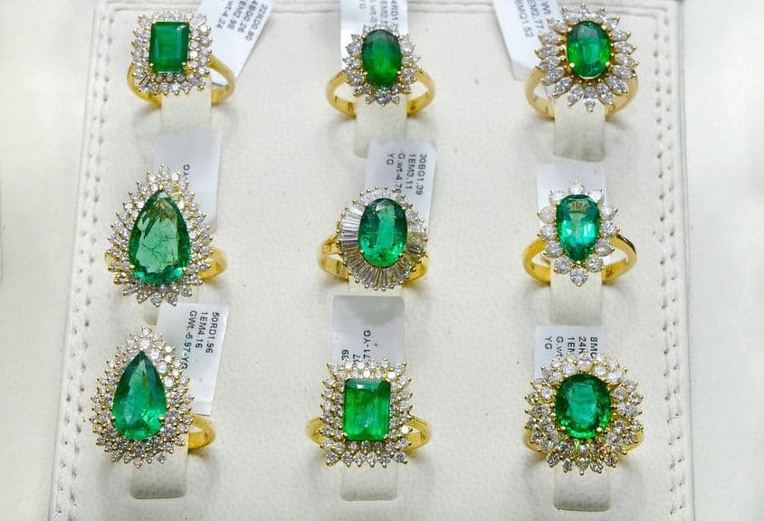 Anillos de esmeralda rodeados de diamantes en un aro de oro.