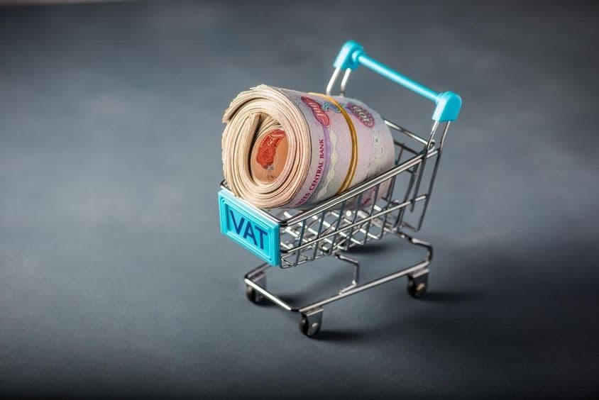 Carrito de compras pequeño con un fajo de dirhams y la palabra 'impuesto' al frente.