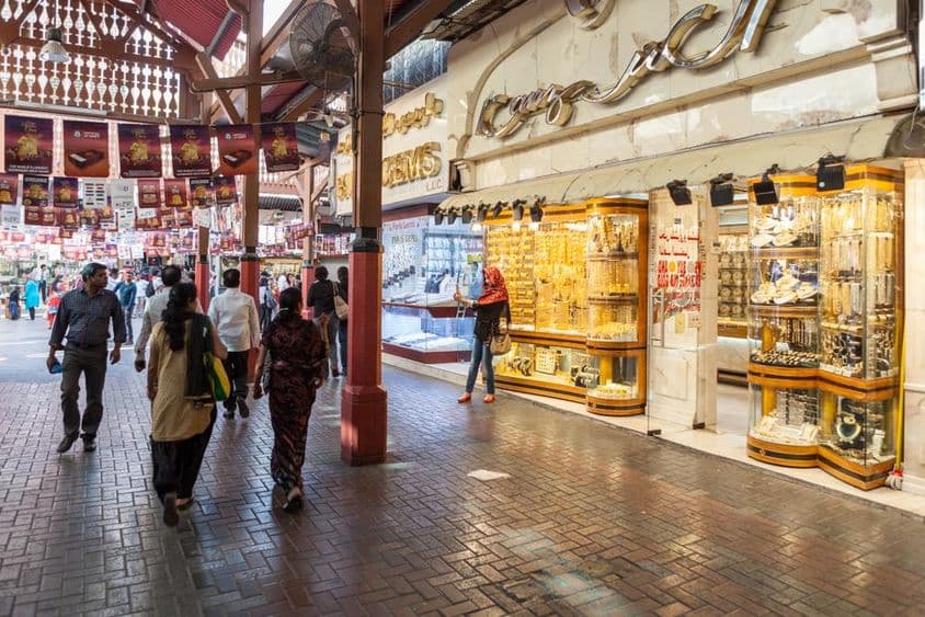 Mercado de oro de Dubái, una tienda mostrando joyería de oro, con personas paseando.