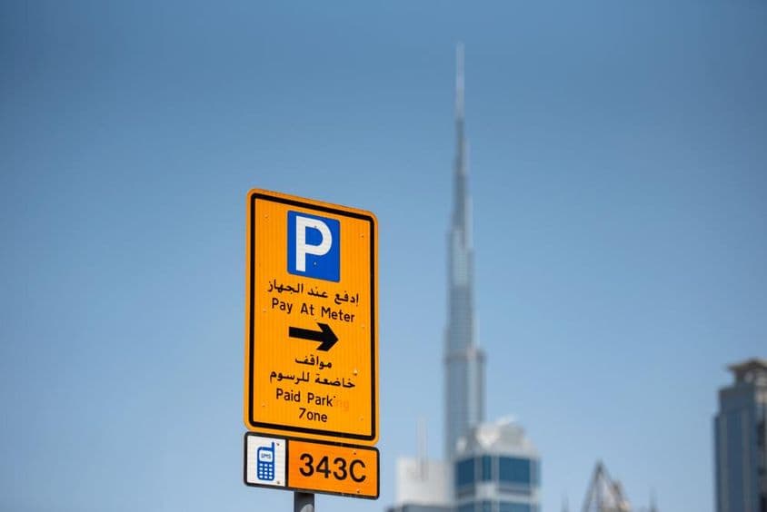 Señal de estacionamiento con código de zona, Burj Khalifa al fondo.
