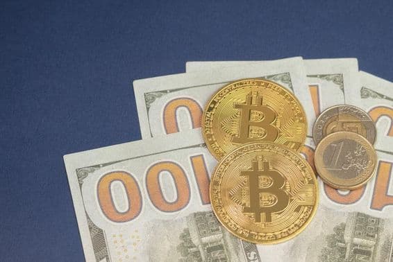 Dólar estadounidense sobre monedas de bitcoin junto a una moneda de 1 euro