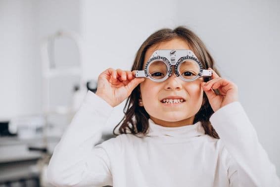 Niña con discapacidad visual usando gafas de prueba en una óptica.