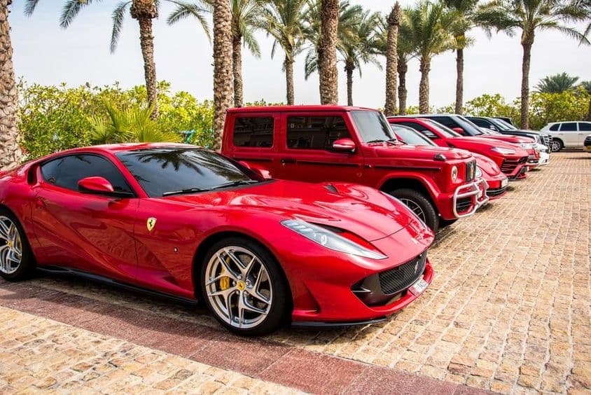 Coches de lujo rojos alineados en Dubái, destacando Ferrari, Porsche, Mercedes.