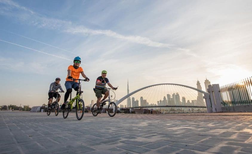 Ciclistas con cascos frente al Burj Khalifa.