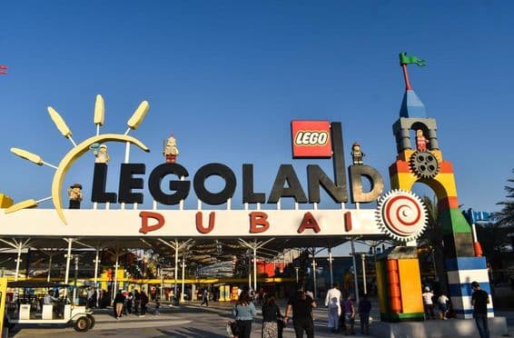 Entrada a LEGOLAND Dubái con personas y un carrito de golf al frente.