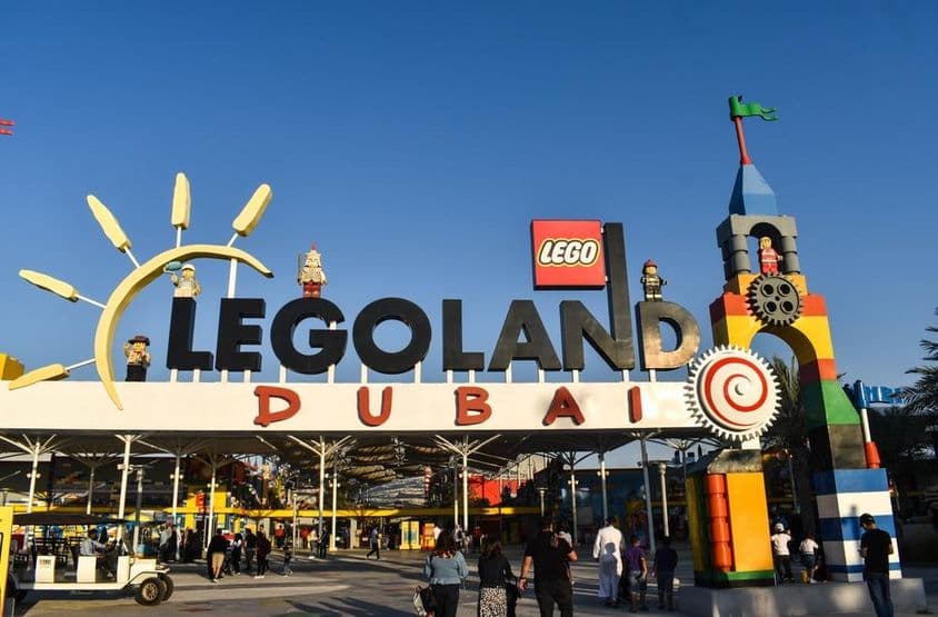 Entrada a LEGOLAND Dubái con personas y un carrito de golf al frente.