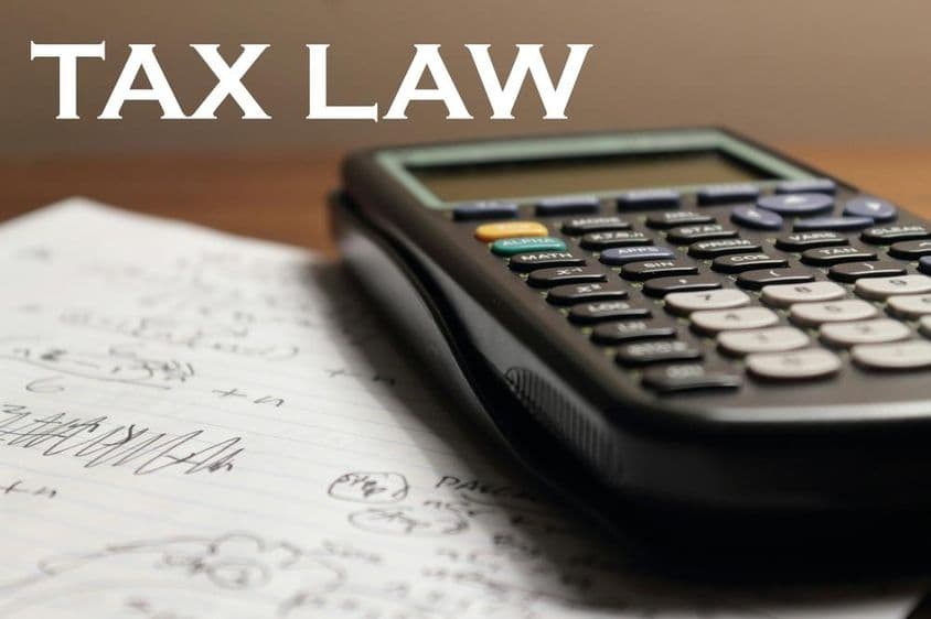 Una calculadora está sobre un cuaderno con la etiqueta legislación fiscal arriba.