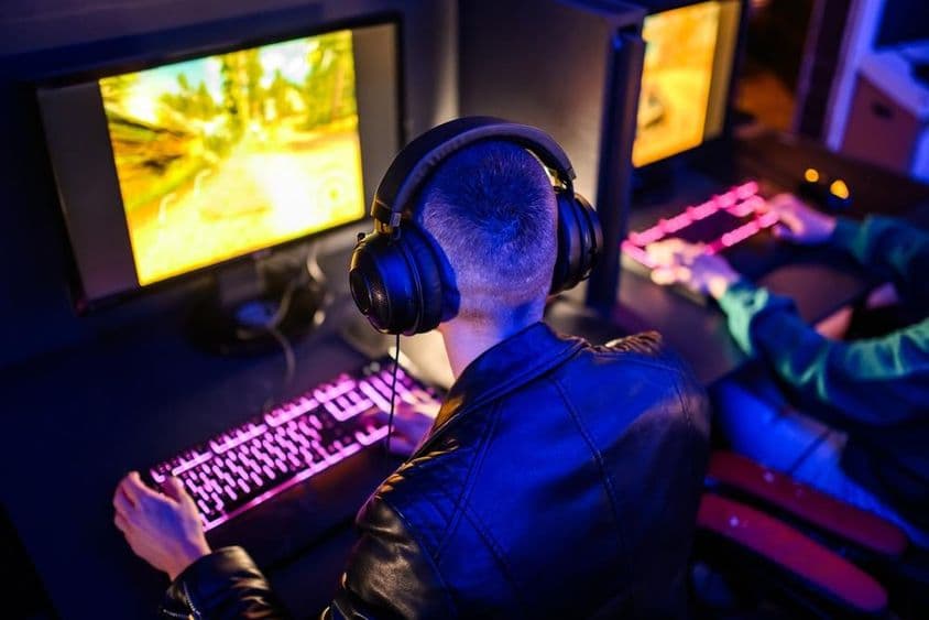 Jugadores en línea visibles, con teclado y monitor iluminados delante.