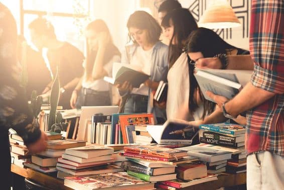Estudiantes explorando libros en una gran feria.