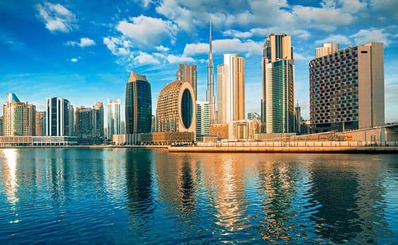 Rascacielos de Dubái con agua en primer plano, Burj Khalifa al fondo.