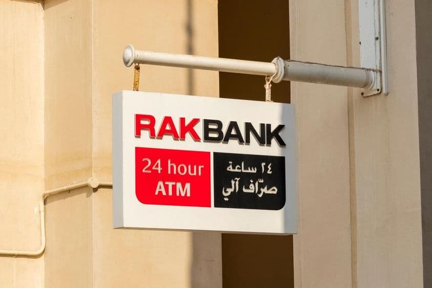 Cartel de cajero automático de RAKBANK en texto rojo y parcialmente negro.