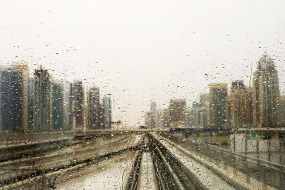 Ventana empapada de lluvia con vista a rascacielos.