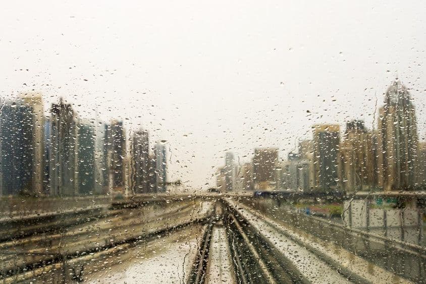Ventana empapada de lluvia con vista a rascacielos.