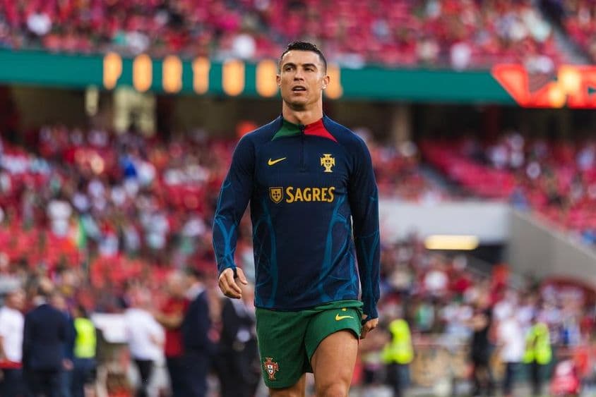 Cristiano Ronaldo en el campo con camiseta azul y pantalones cortos verdes.