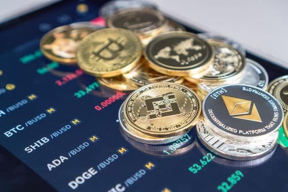 Monedas de Ethereum y Bitcoin colocadas sobre una pantalla de teléfono que muestra tasas de cambio de criptomonedas.