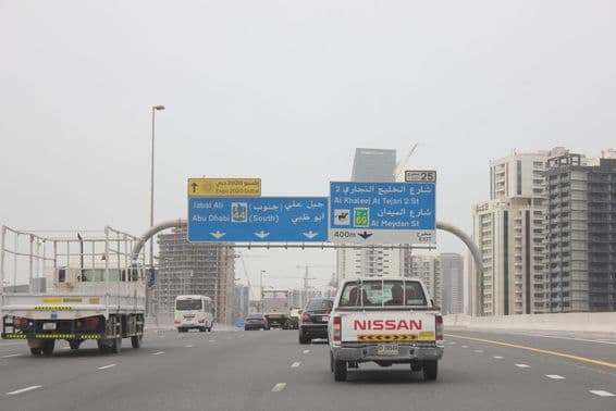 Señal vial de carretera Al Khail, con algunos edificios altos en el fondo.