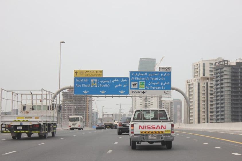 Señal vial de carretera Al Khail, con algunos edificios altos en el fondo.