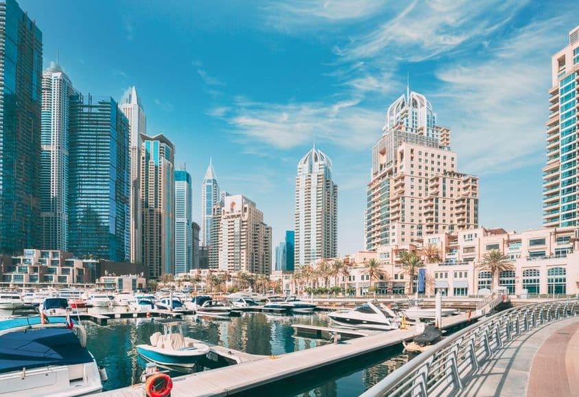 Línea del horizonte de Dubai Marina con barcos en el puerto, rascacielos al fondo.