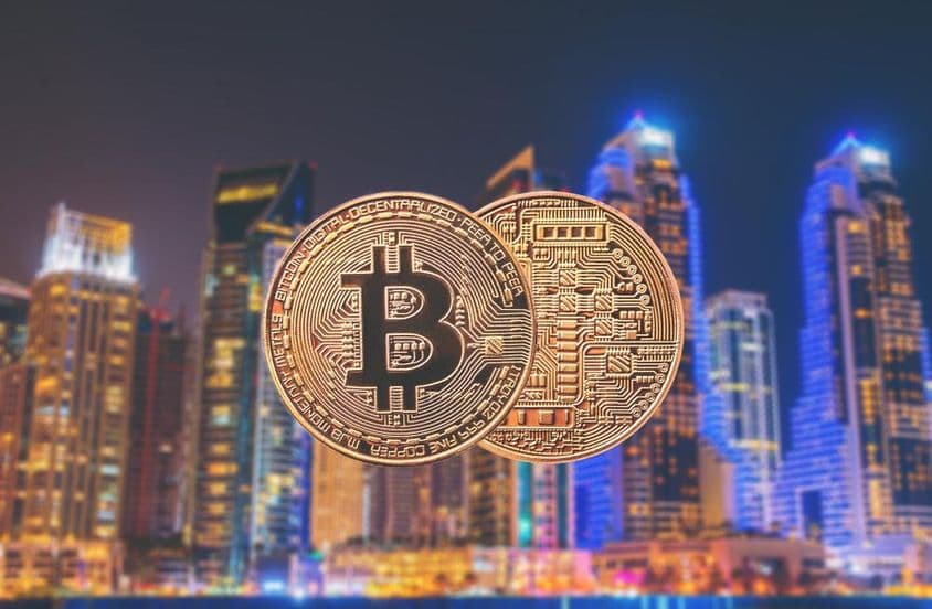 Monedas de Bitcoin en primer plano con rascacielos de fondo.