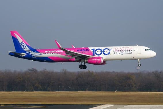 Avión de Wizz Air volando a baja altitud sobre la pista.
