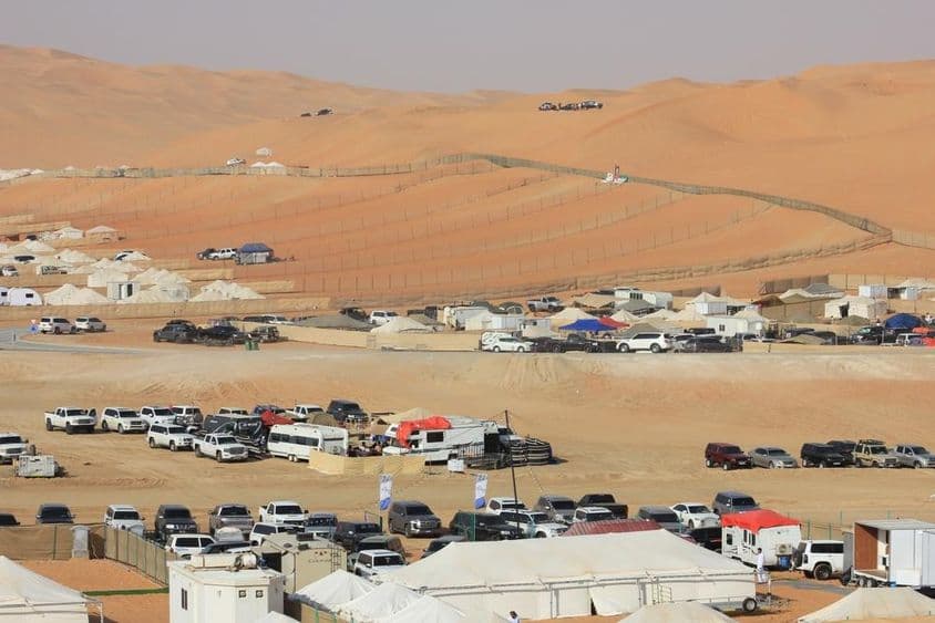Escenario del Festival Internacional de Liwa en el desierto con coches, autocaravanas y tiendas de campaña.