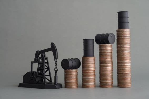 Mini plataforma petrolera y monedas apiladas con un barril de petróleo en la parte superior.