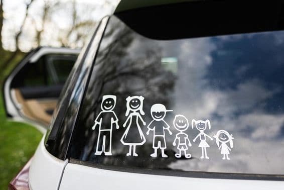 La luneta trasera de un coche muestra una pegatina de una familia, incluyendo 2 adultos y 4 niños.