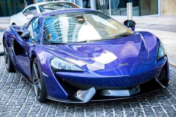 Coche azul McLaren estacionado en una calle de Dubái.