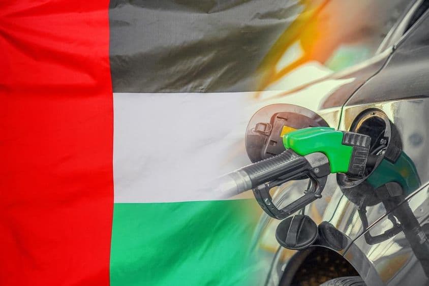 Un automóvil siendo abastecido de gasolina, con la bandera de EAU de fondo.
