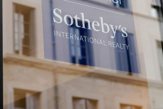 Cartel de Sotheby's visible en el frente de un edificio, en una placa transparente.
