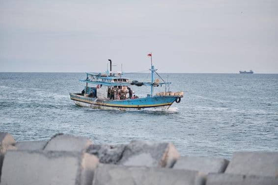 Un barco pesquero desgastado en el mar con personas a bordo.