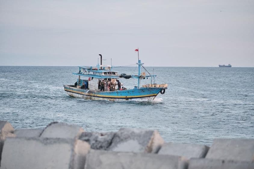Un barco pesquero desgastado en el mar con personas a bordo.