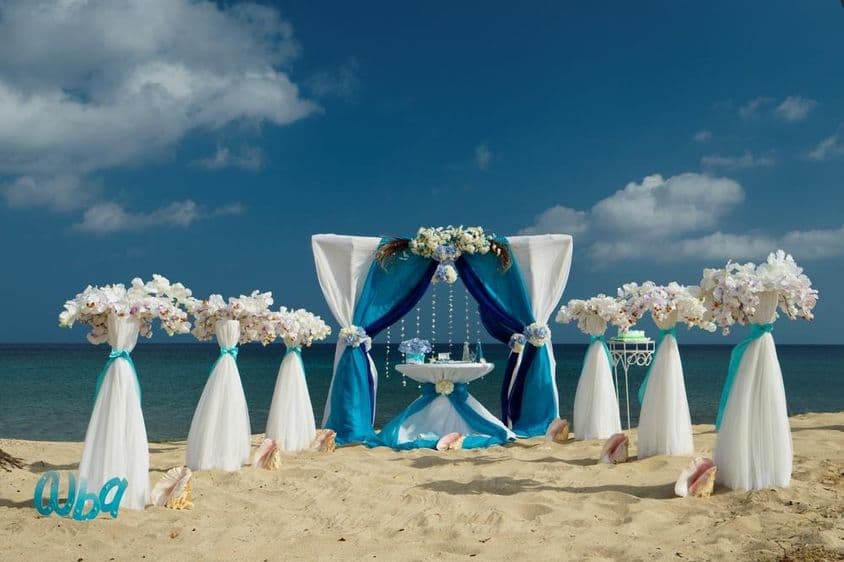 Boda en la playa sobre arena con flores y pequeña mesa