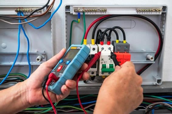 Electricista revisando una fuente de energía con un medidor.