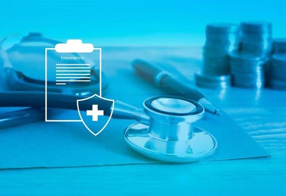 Seguro de salud en primer plano, fondo con un estetoscopio y monedas pequeñas.