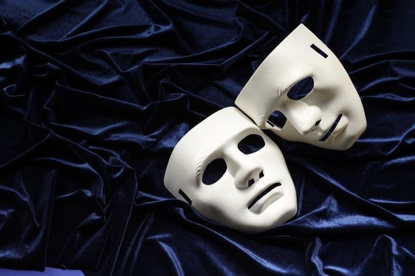 Teatro, dos máscaras blancas sobre terciopelo azul.