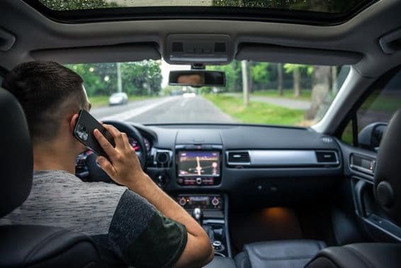 Joven usando su teléfono mientras conduce un coche.