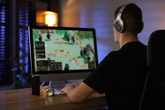 Un niño mayor juega un videojuego en una computadora en un escritorio.