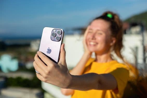 Joven sosteniendo un teléfono iPhone.
