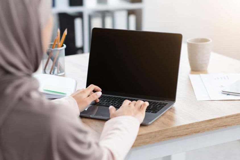 Mujer musulmana trabajando en una computadora portátil.