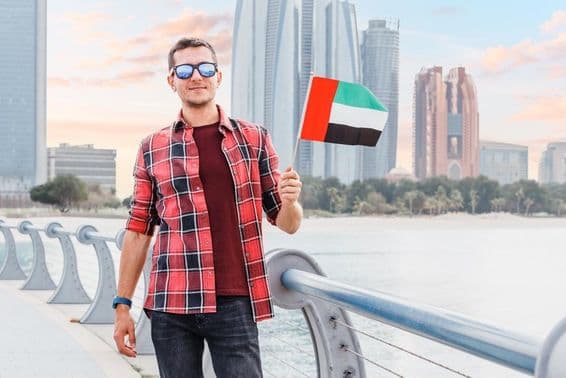 Joven en Dubai Marina sosteniendo una bandera de los EAU.