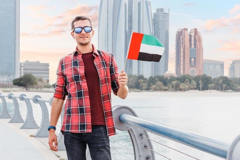 Joven en Dubai Marina sosteniendo una bandera de los EAU.