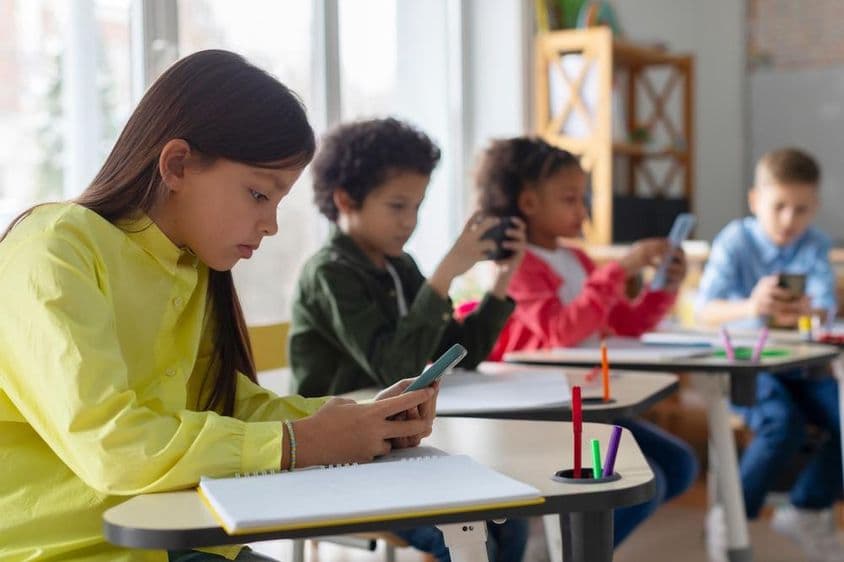Niños usando teléfonos en un aula.