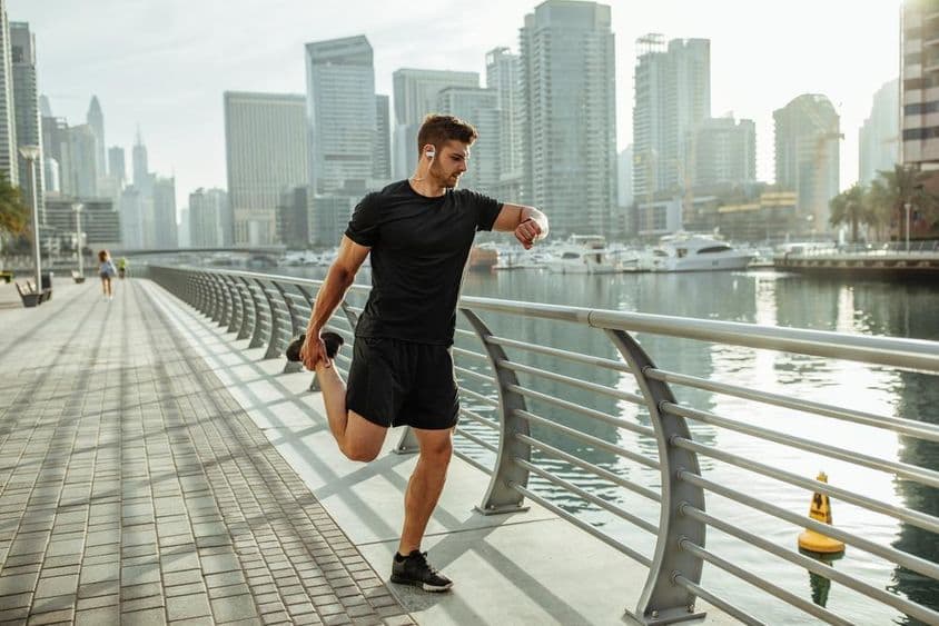 Joven estirándose después de correr junto al canal de Dubái.
