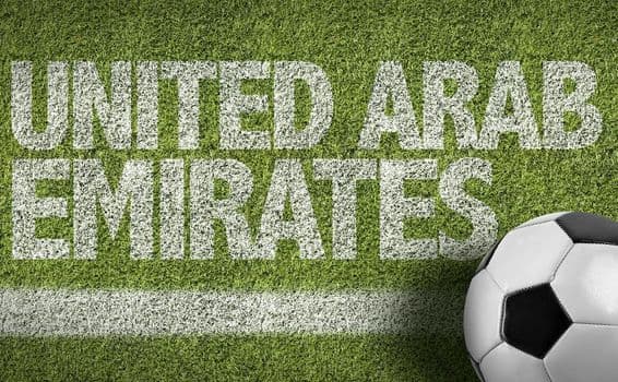 Inscripción 'EAU' pintada en el césped con un balón de fútbol.