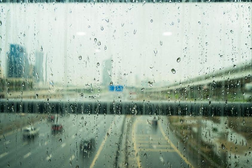 Gotas de lluvia en una ventana con algunos rascacielos desenfocados al fondo.